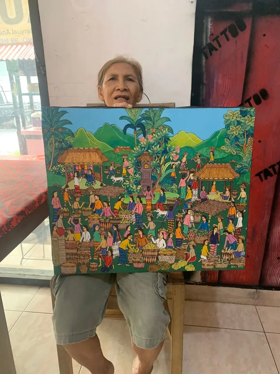 Jero Wayan Amer Ambarie holding one of her earlier paintings