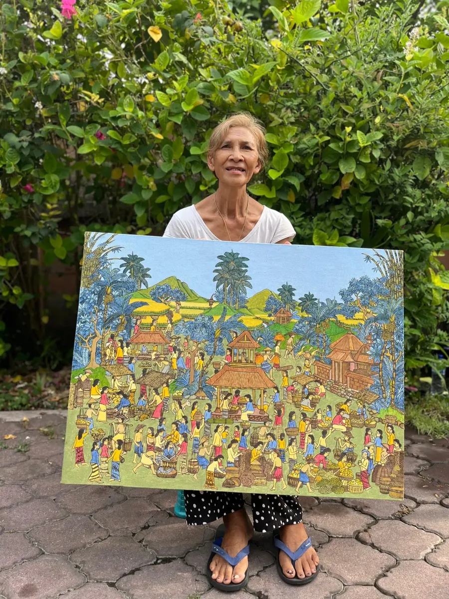 Jero Wayan Amer Ambarie holding one of her earlier paintings