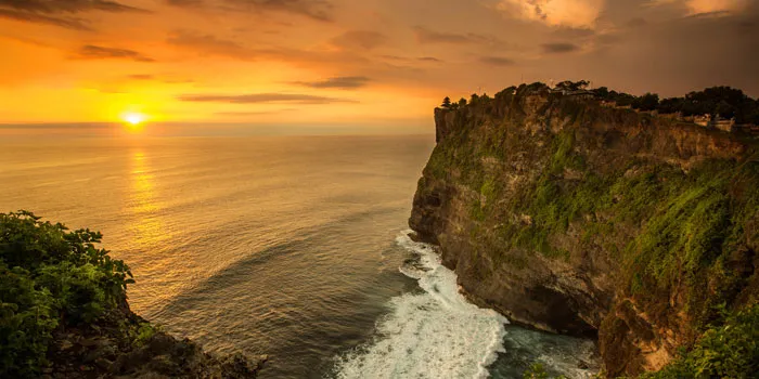 Uluwatu Temple perched on dramatic limestone cliffs above the Indian Ocean at sunset